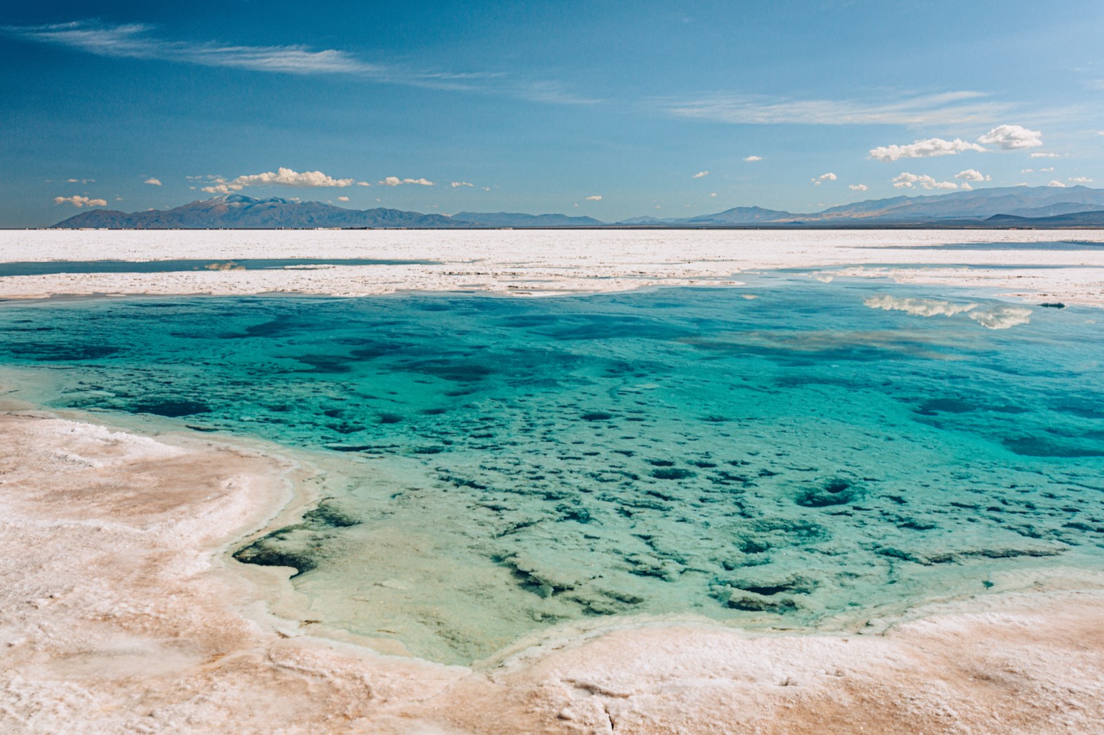 A turquoise brine pool cut into the white crust of the Salinas Grandes
